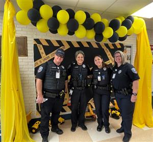 4 officers standing under yellow and black balloons